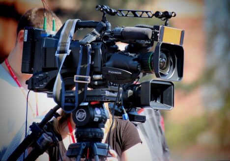 Three people standing behind TV camera