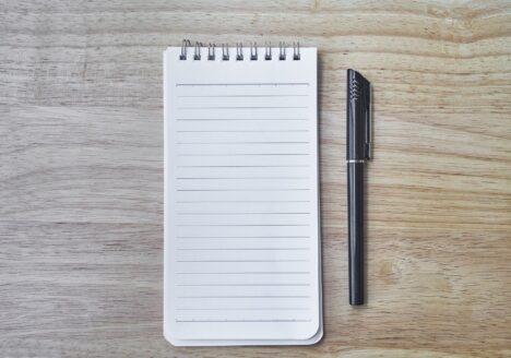 Lined notepad and pen on wood table