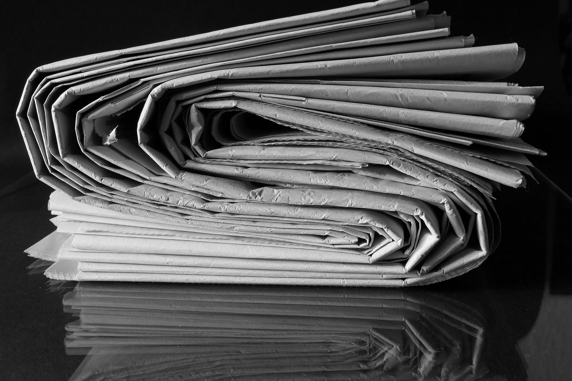 Stack of newspapers curved in s-shape, in black and white