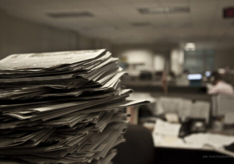 Stack of newspapers in foreground of office
