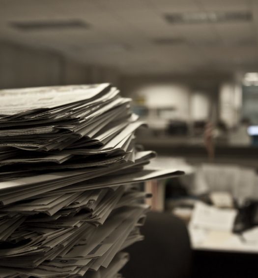 Stack of newspapers in foreground of office