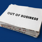 Stack of newspapers with blank sheet on top that says "Out of business" in all caps, black block letters, over dark blue background