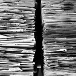 Two stacks of documents in file folders in black and white