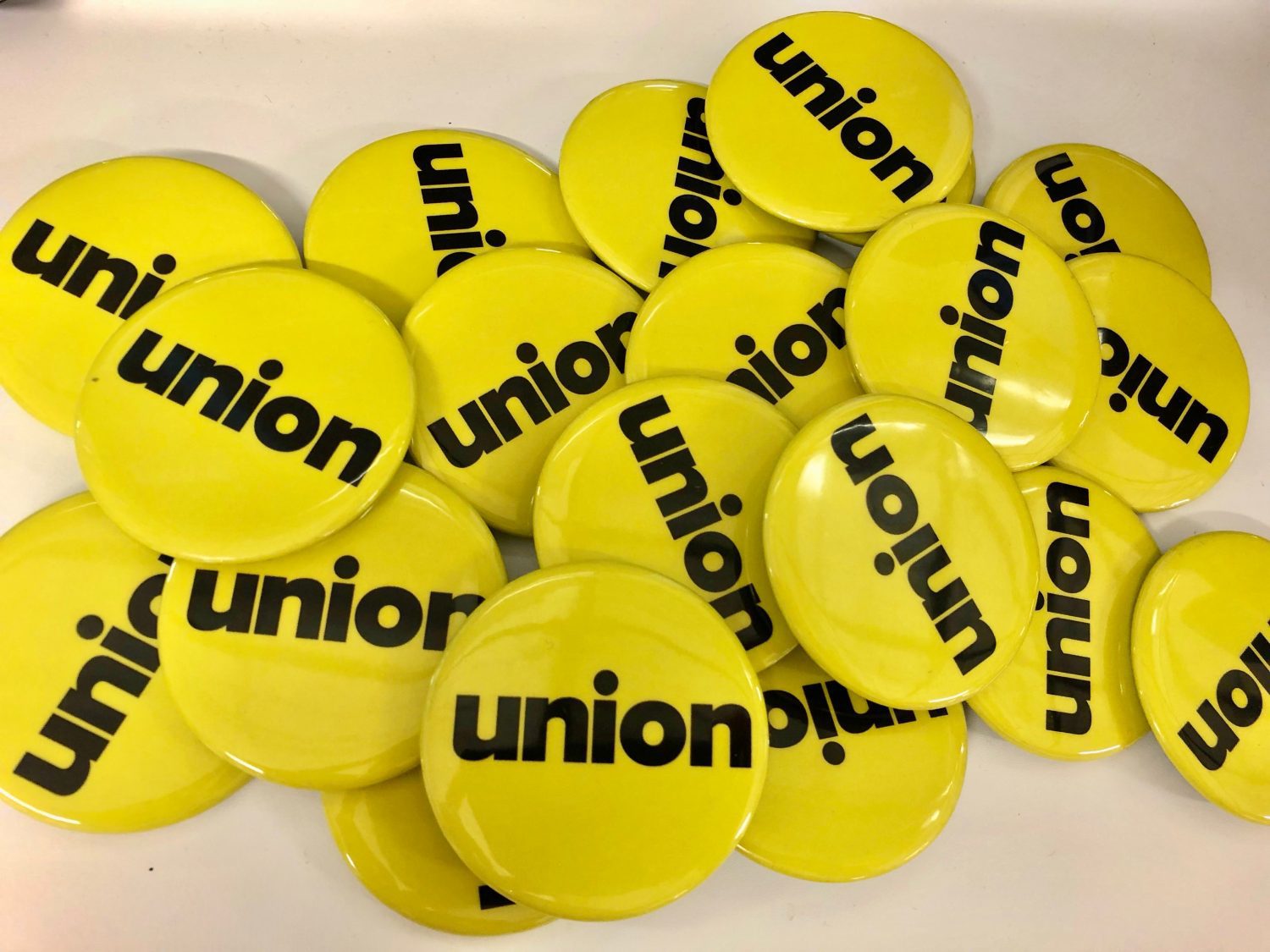 Pile of yellow pin buttons with black text "union"