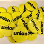 Pile of yellow pin buttons with black text "union"