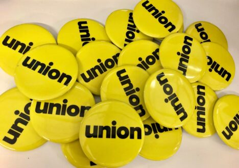 Pile of yellow pin buttons with black text "union"