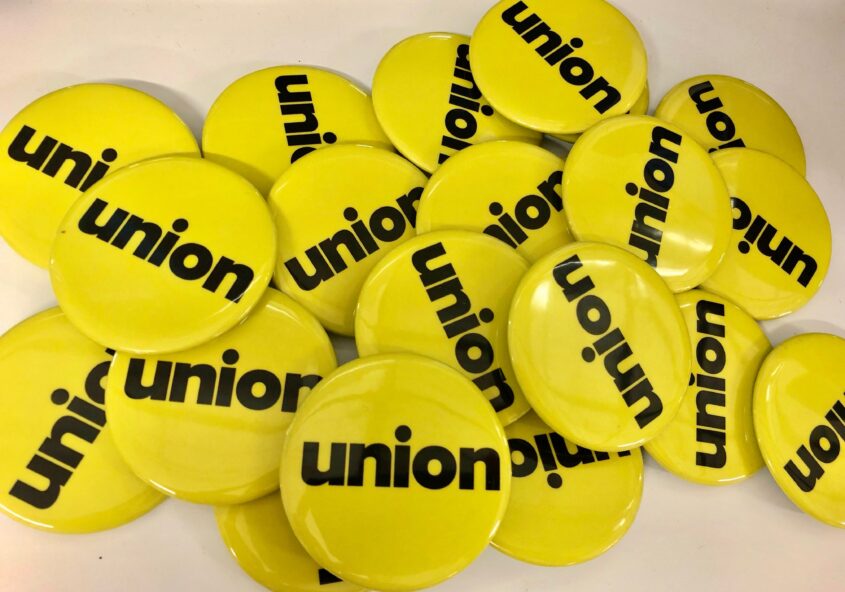 Pile of yellow pin buttons with black text "union"