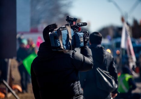 Back of person holding tv camera outside