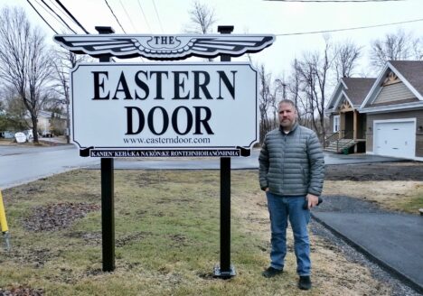 Steve Bonspiel stands in front of Eastern Door sign