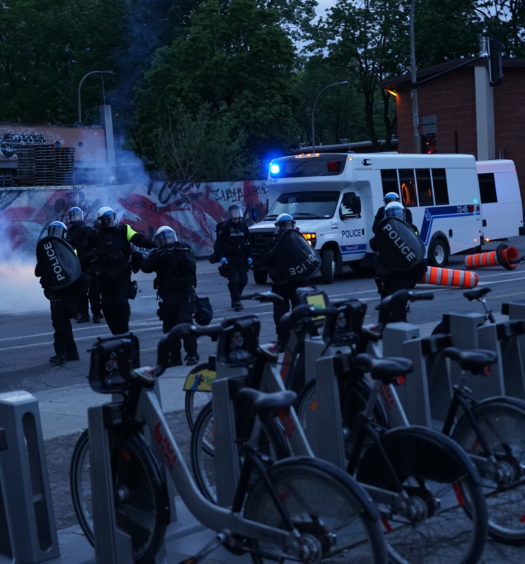 Police aiming a grenade launcher at journalists and a first aid table in front of Saint-Laurent Metro Station on May 31, 2020