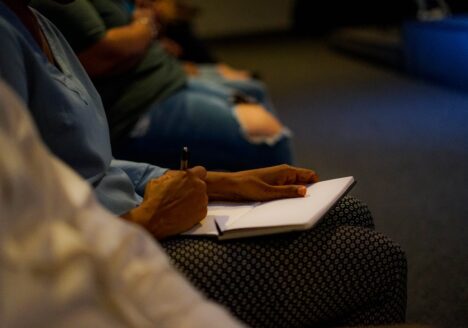 Student writing in a notebook on lap