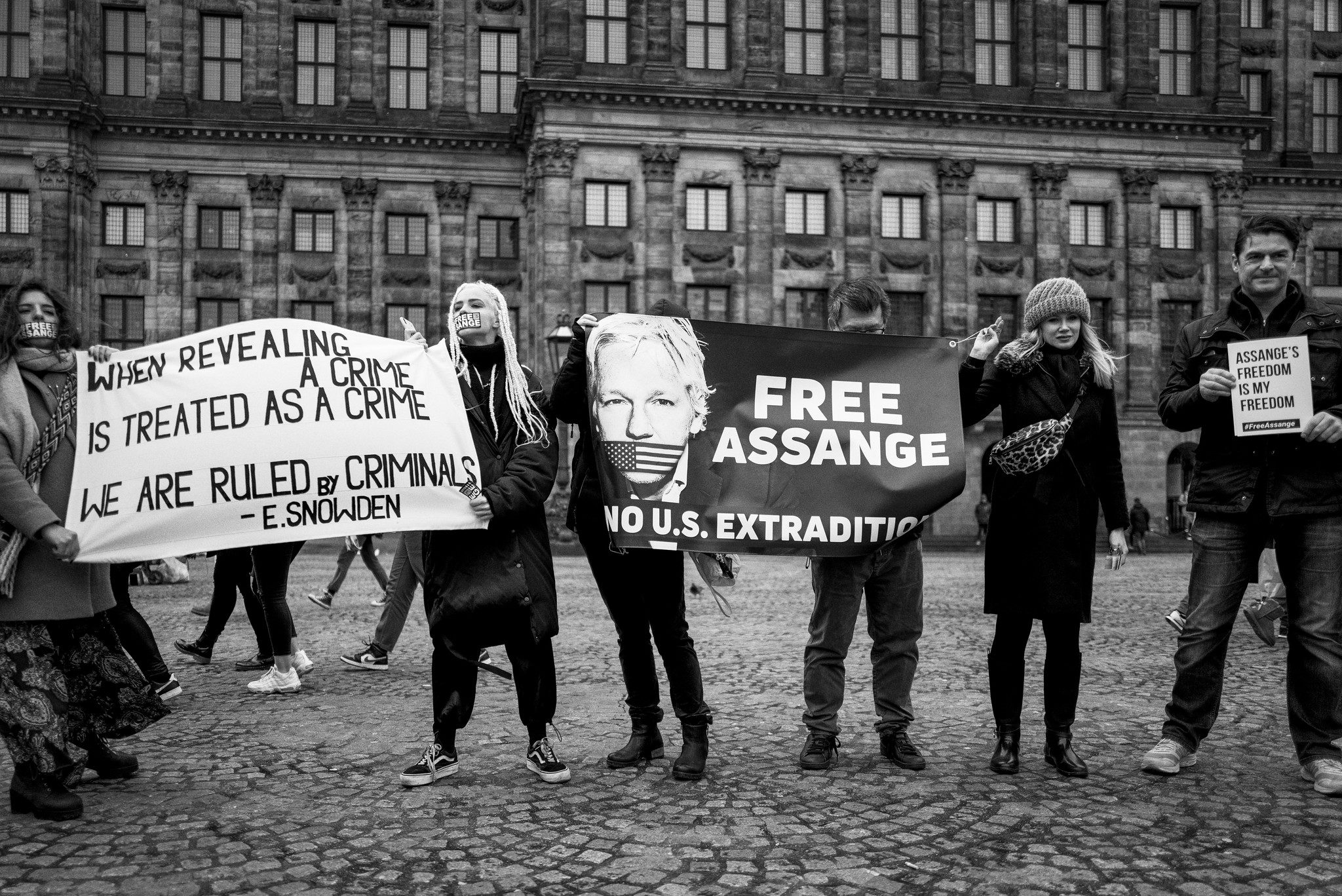 A group of people outside holding signs supporting Julian Assange, including one that says "Free Assange, no U.S. extradition"
