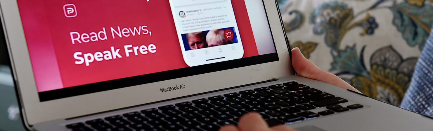 Person holding laptop with Parler open on screen