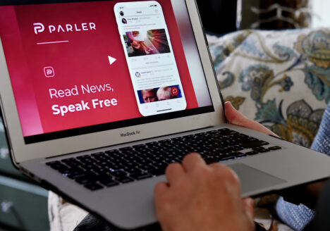 Person holding laptop with Parler open on screen
