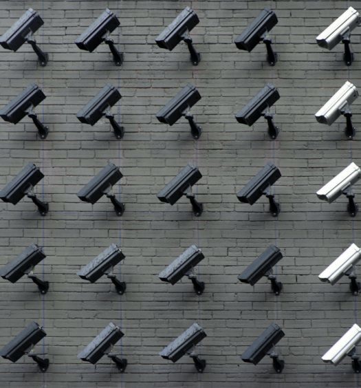 A brick wall of black and white surveillance cameras pointing down.