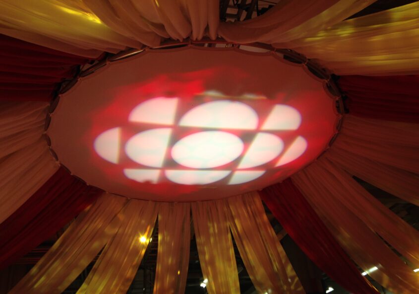 CBC red and white logo projected on ceiling surrounded by draperies.