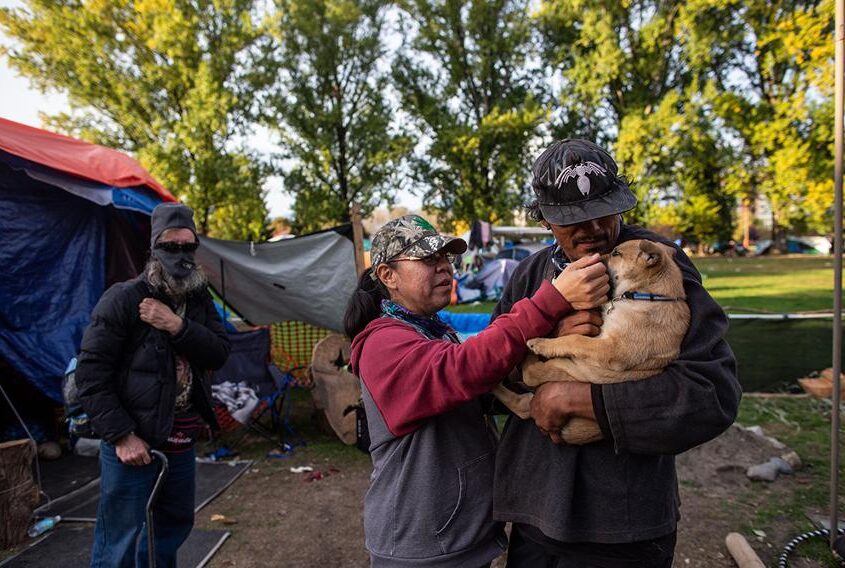 William Tomorowski and his partner Honey Turner play with their puppy Kalypso in the yard of their campsite at the Strathcona Park homeless encampment.