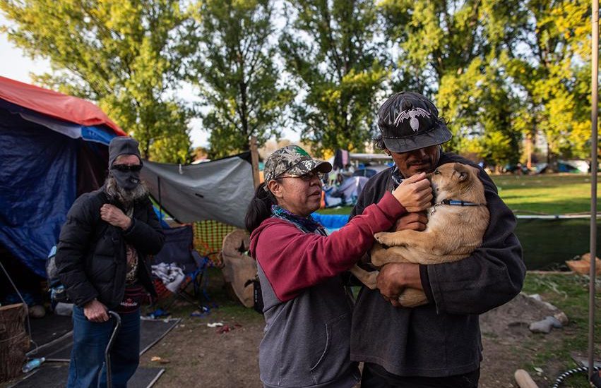 William Tomorowski and his partner Honey Turner play with their puppy Kalypso in the yard of their campsite at the Strathcona Park homeless encampment.
