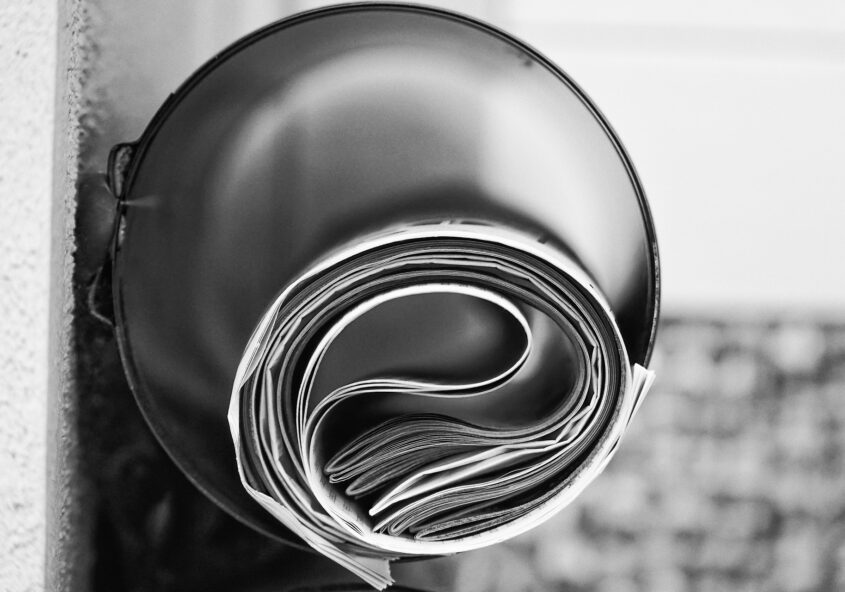 Black and white image of newspaper rolled up inside of tube
