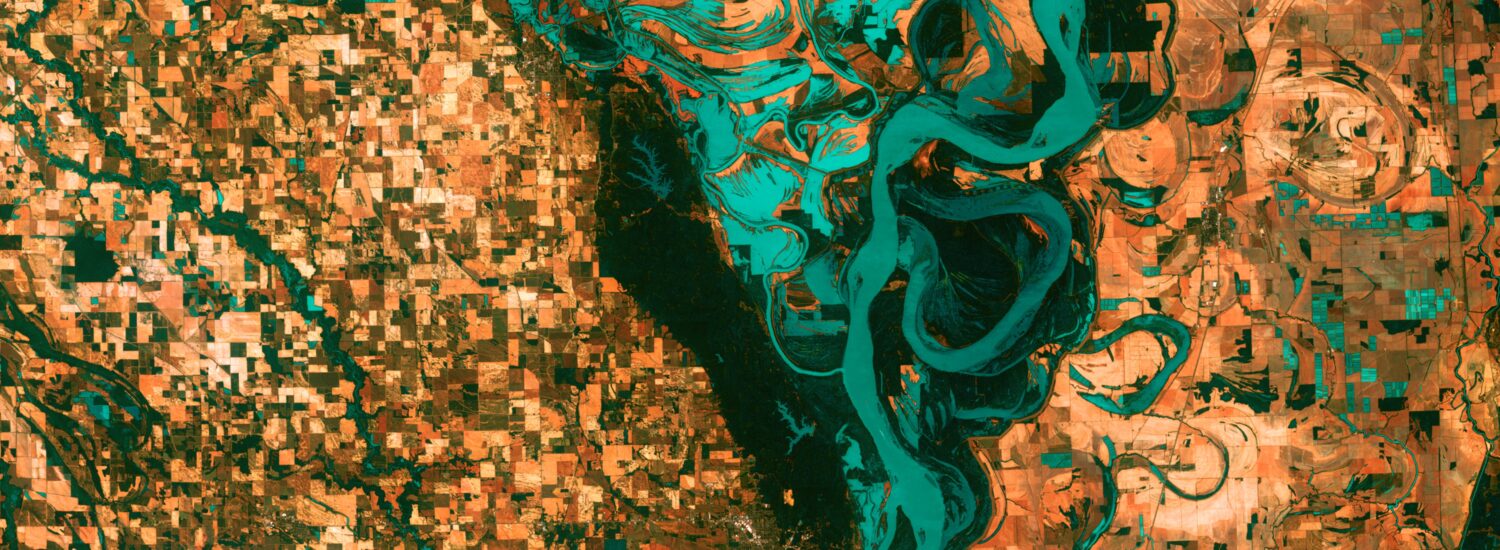 Small, blocky shapes of towns, fields, and pastures surround the graceful swirls and whorls of the Mississippi River. Countless oxbow lakes and cutoffs accompany the meandering river south of Memphis, Tennessee, on the border between Arkansas and Mississippi, USA. The "mighty Mississippi" is the largest river system in North America.