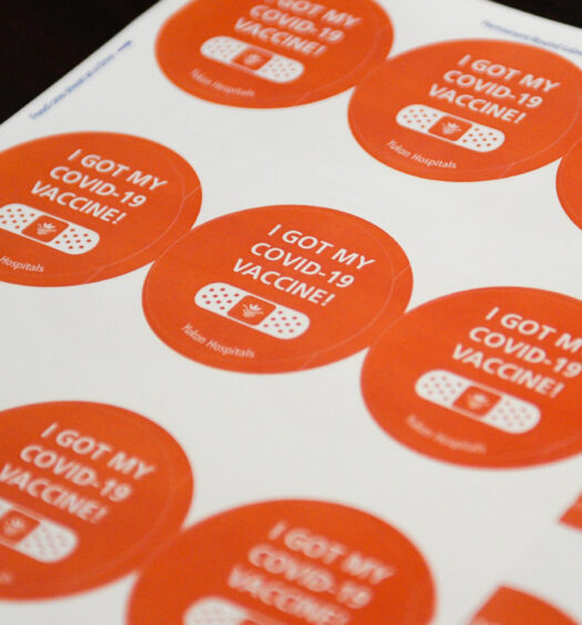A sheet of 9 orange COVID-19 vaccination stickers on white paper, that say "I GOT MY COVID-19 VACCINE!" with a drawing of a bandaid underneath. Bottom reads "Yukon Hospitals"