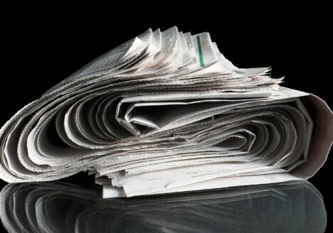 Newspaper rolled in S-curve on black background