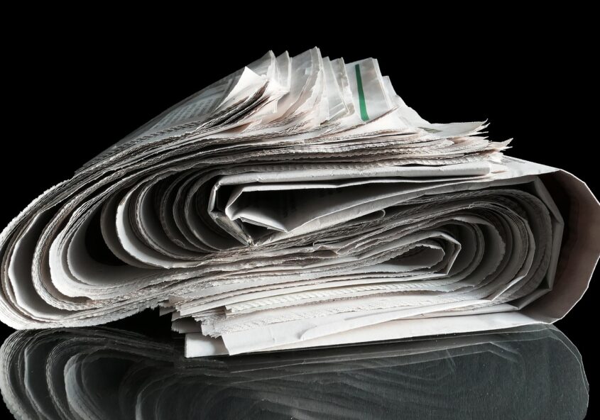 Newspaper rolled in S-curve on black background