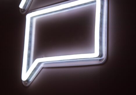 Neon white chat bubble on black background.