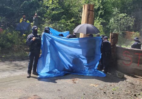 RCMP using tarps to obstruct media access as an arrest takes place last week.
