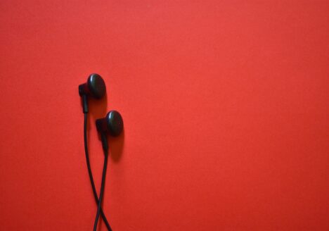 Black earbud headphones on red background