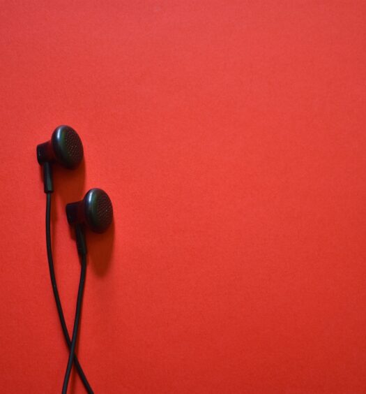Black earbud headphones on red background