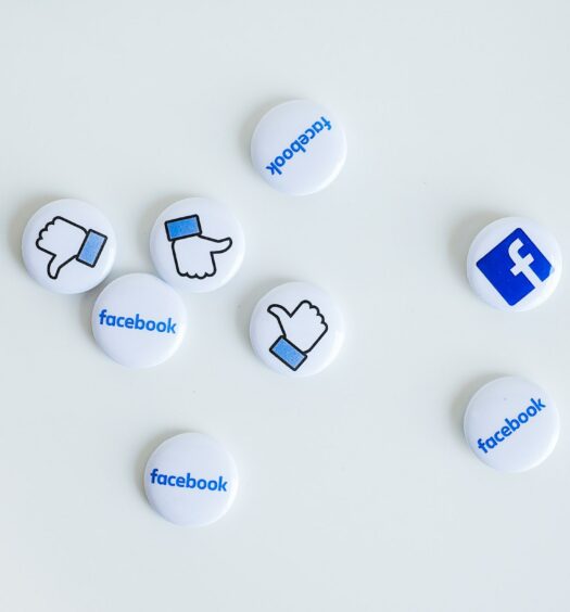 Buttons with blue Facebook name, logo and like icon on a white surface