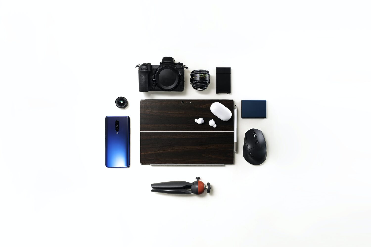 Smart phone, laptop, camera, lens, computer mouse and earbuds on white background