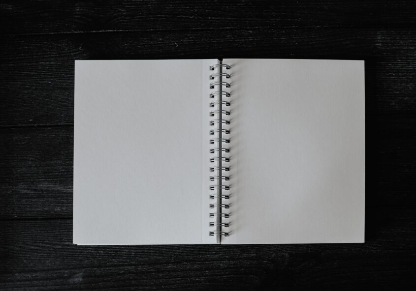 Blank spiral-bound notebook open on black background