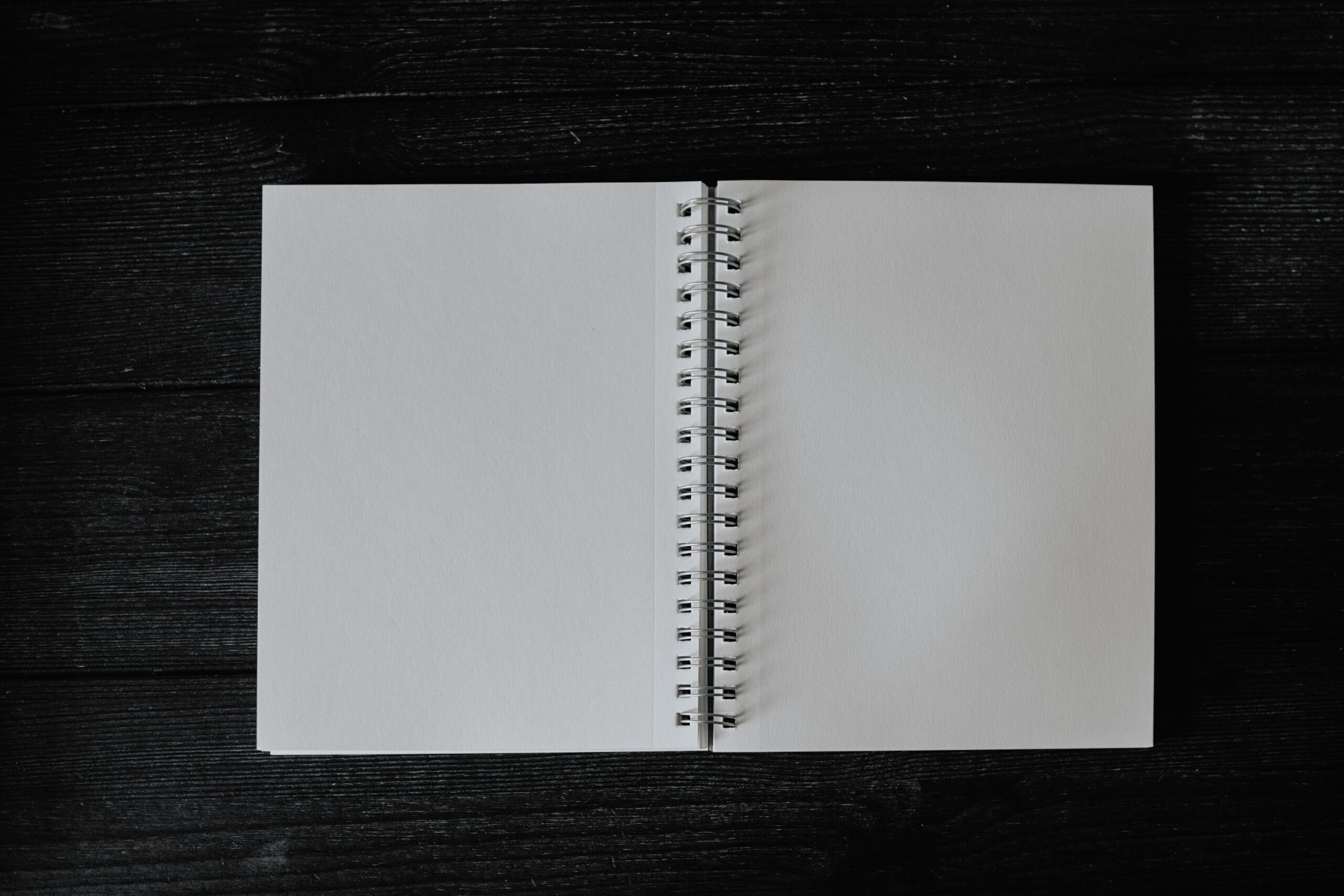 Blank spiral-bound notebook open on black background