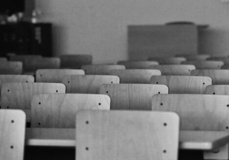 Staggered rows of classroom chairs and desks in black and white