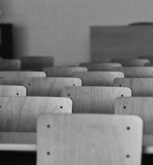 Staggered rows of classroom chairs and desks in black and white