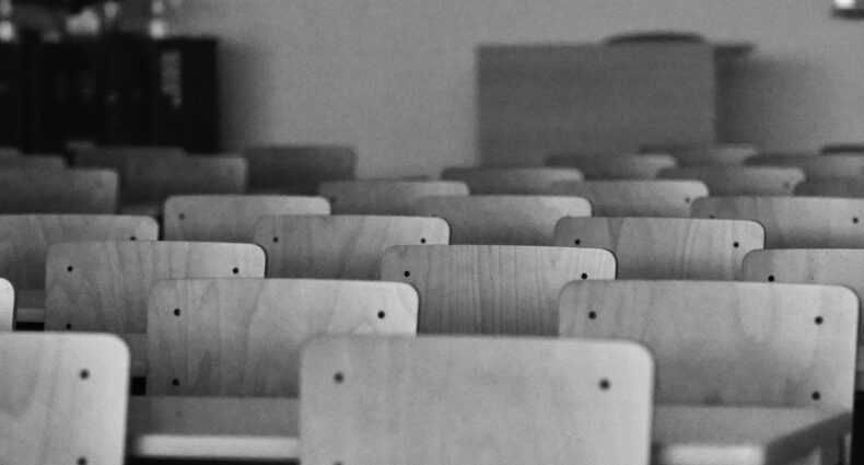 Staggered rows of classroom chairs and desks in black and white