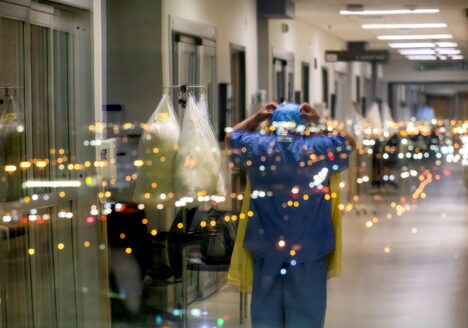 A nurse is reflected in a window as she puts on personal protective equipment to treat a COVID-19 patient inside the intensive care unit of Humber River Hospital in Toronto on April 20, 2021.