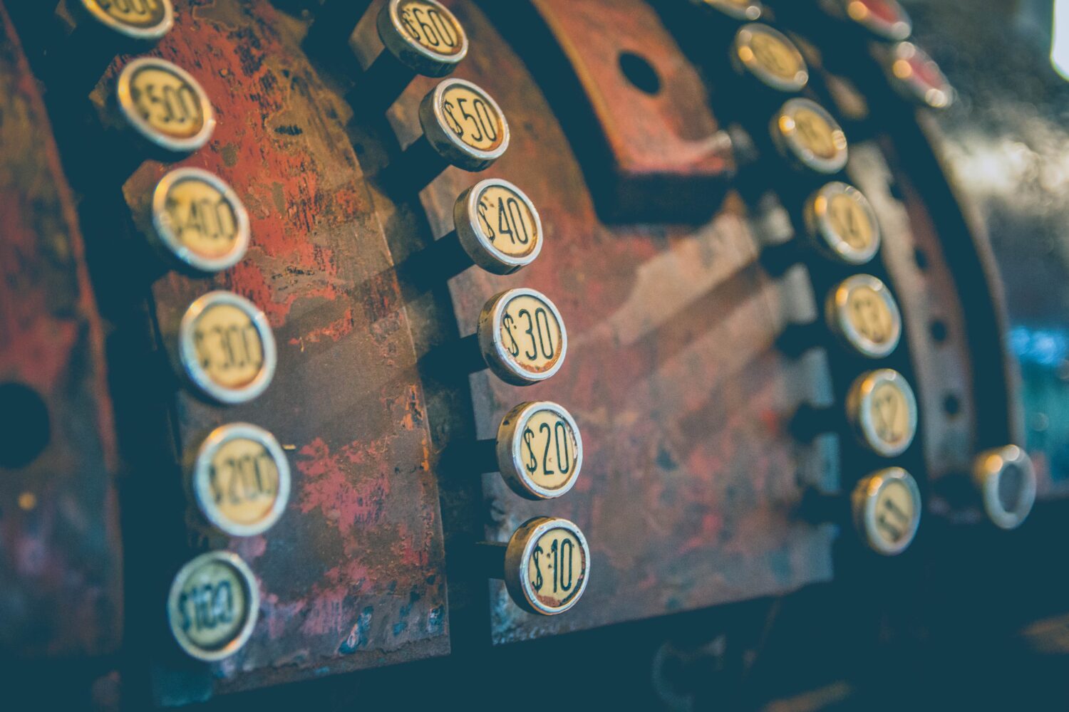 Close-up of antique cash register with circular buttons with dollar amounts.