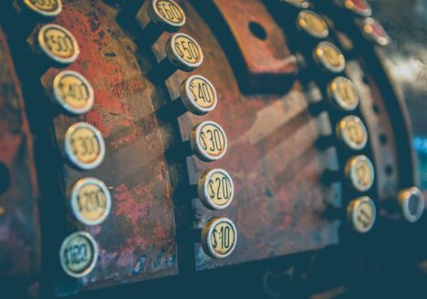 Close-up of antique cash register with circular buttons with dollar amounts.