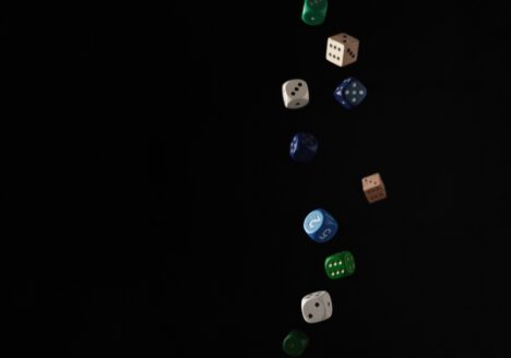 Multi-coloured dice falling in front of black background