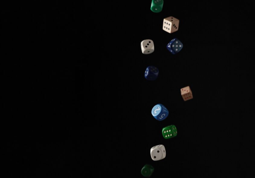 Multi-coloured dice falling in front of black background
