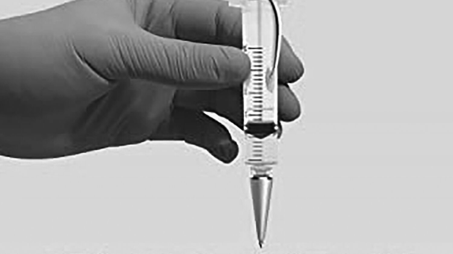 Gloved hand holds syringe vertically