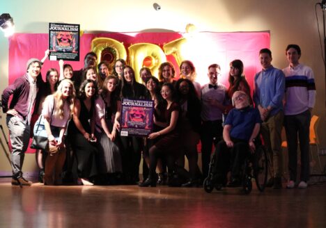 Steve Trumper (first row, right) in a group photo with the masthead that produced the 2019 issue of the Review of Journalism. A student in the front and back row hold up a poster of the magazine's cover.