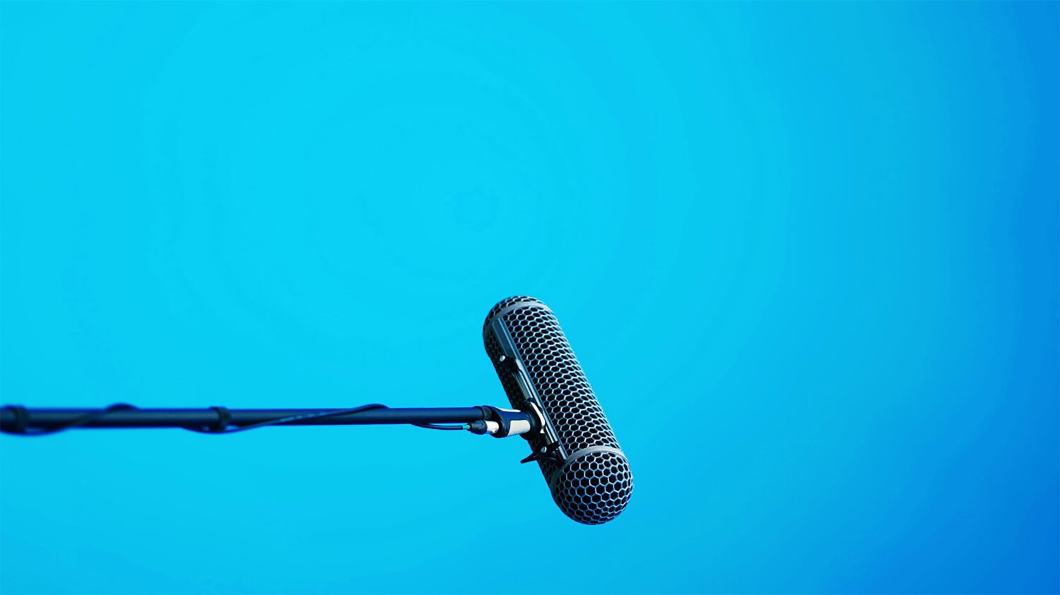 Horizontal microphone on stand over light blue background