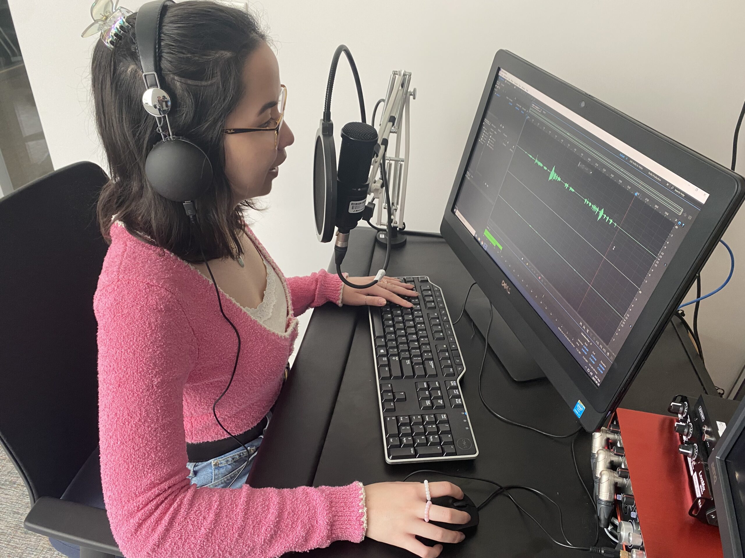 Kendra Seguin wearing headphones recording audio at a computer station.