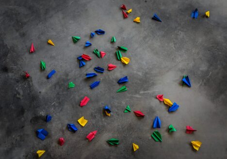 Red, blue, green and yellow paper planes on ground