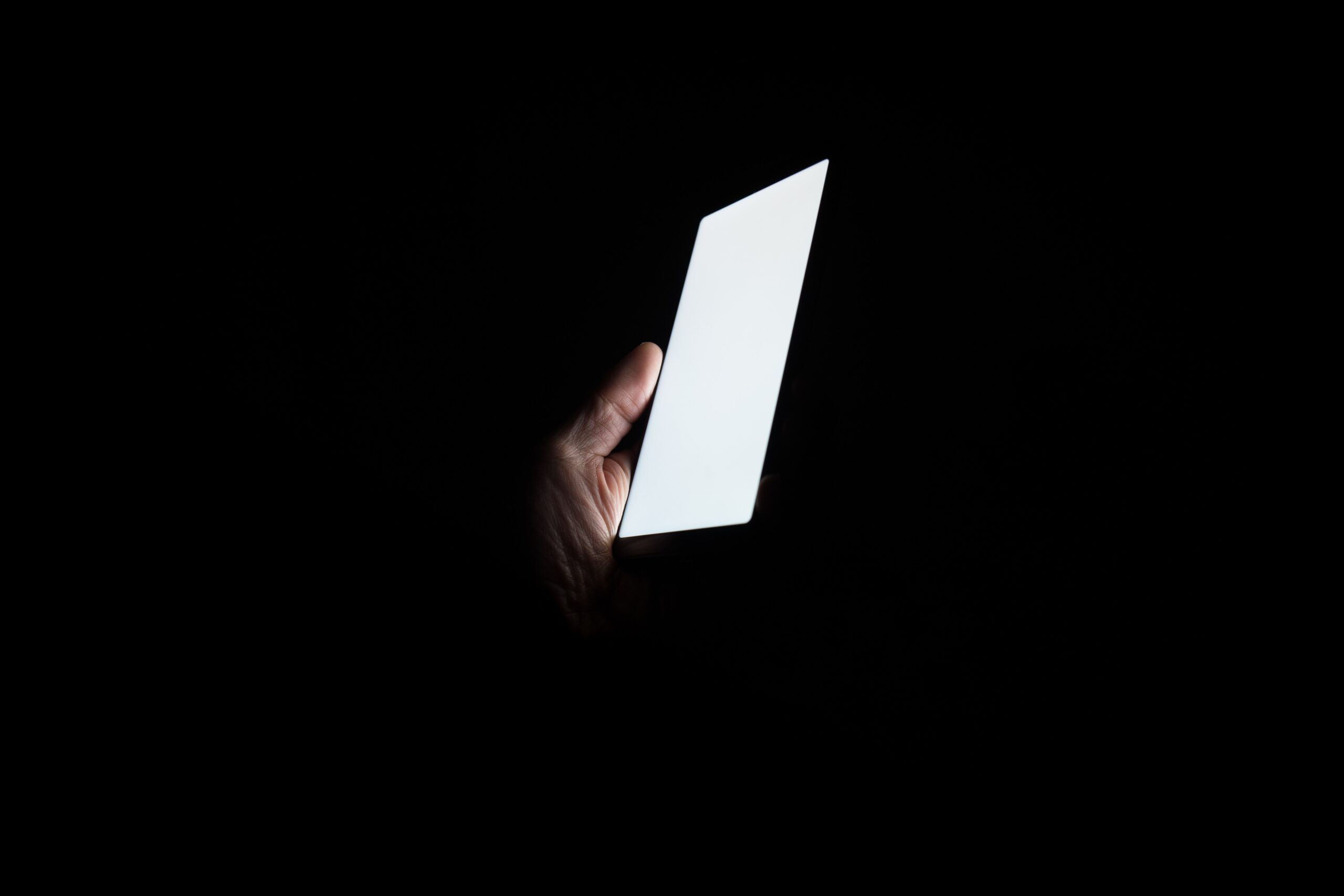 White phone screen held in dark room