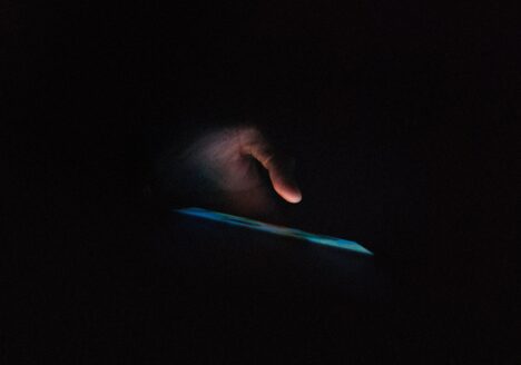 Hand holding smartphone in dark room